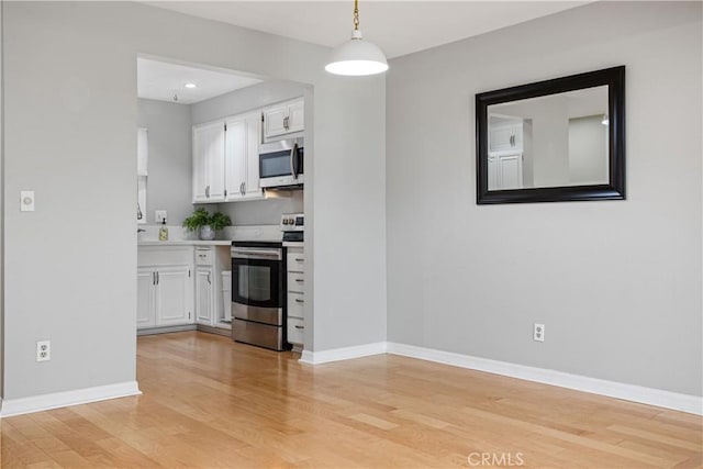 kitchen with white cabinetry, pendant lighting, light hardwood / wood-style flooring, and appliances with stainless steel finishes