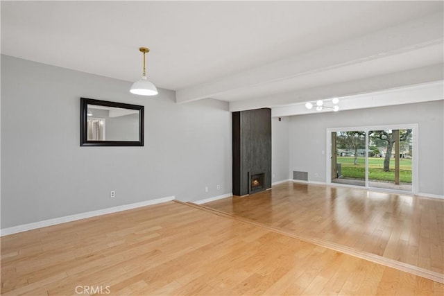 empty room featuring hardwood / wood-style flooring, a fireplace, and beamed ceiling