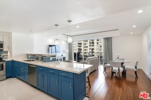 kitchen featuring stainless steel appliances, kitchen peninsula, sink, and blue cabinets