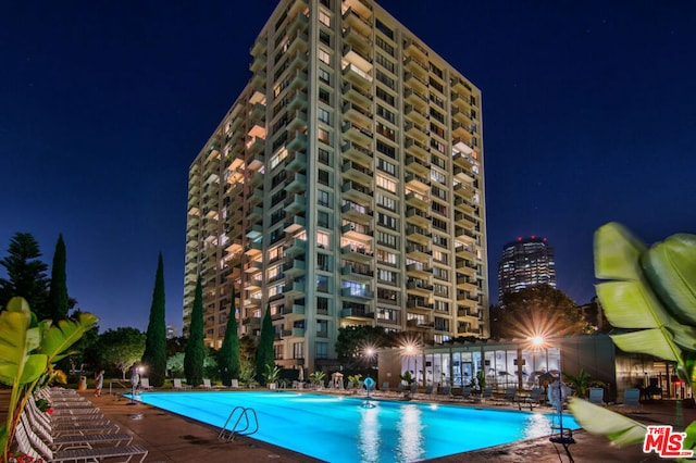 pool at twilight featuring a patio area