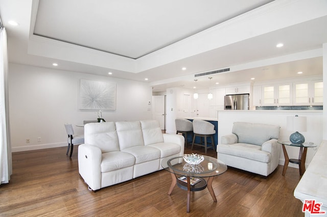 living room featuring a raised ceiling and dark wood-type flooring