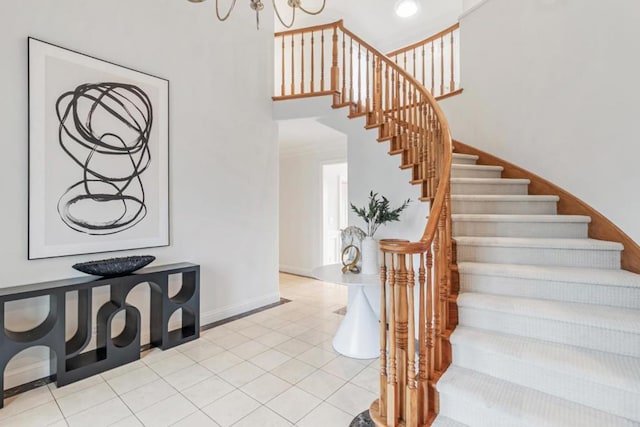 stairway with a chandelier, tile patterned flooring, and a high ceiling