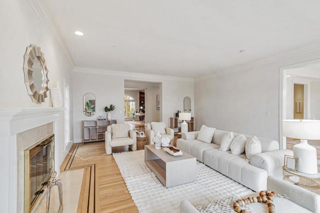 living room with ornamental molding, a high end fireplace, and light hardwood / wood-style flooring