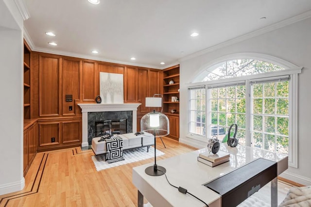 living room featuring built in features, ornamental molding, a premium fireplace, and light wood-type flooring