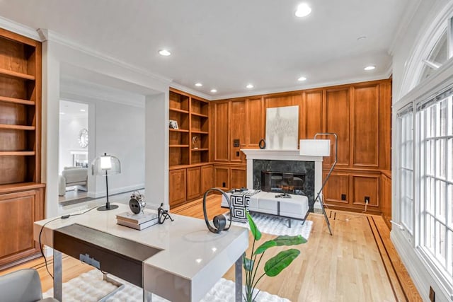 office area featuring ornamental molding, a fireplace, light hardwood / wood-style floors, and built in features