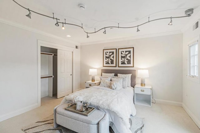 carpeted bedroom featuring track lighting, ornamental molding, and a closet