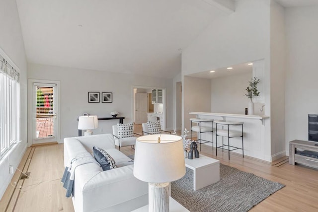 living room featuring beamed ceiling, high vaulted ceiling, and light hardwood / wood-style flooring