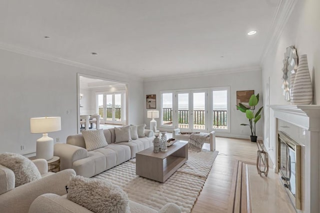 living room featuring a fireplace, ornamental molding, french doors, and light wood-type flooring