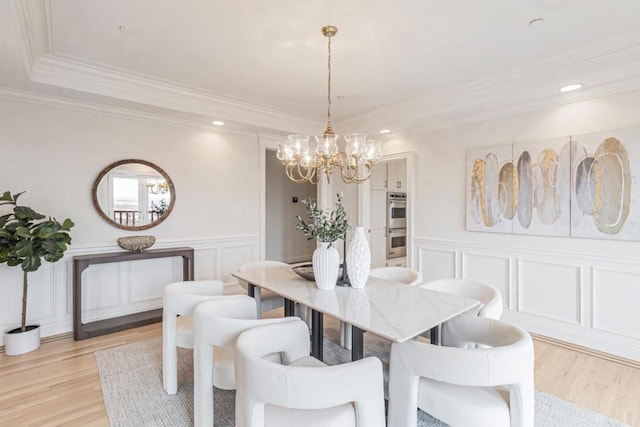 dining area with crown molding, a raised ceiling, light hardwood / wood-style flooring, and a notable chandelier