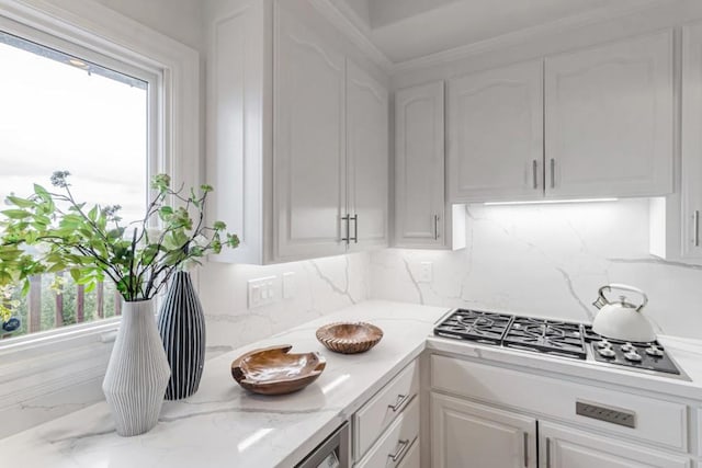 kitchen with white cabinetry, stainless steel gas stovetop, light stone countertops, and tasteful backsplash