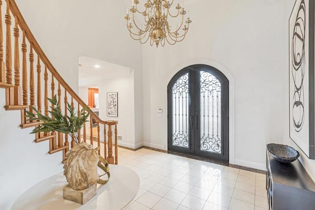 entrance foyer featuring french doors, a towering ceiling, light tile patterned flooring, and an inviting chandelier