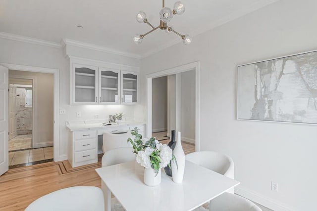 dining space with an inviting chandelier, ornamental molding, and light wood-type flooring