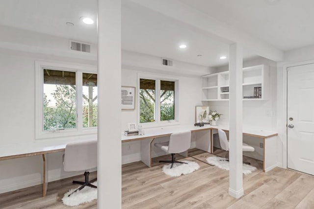 office space with built in desk and light hardwood / wood-style floors