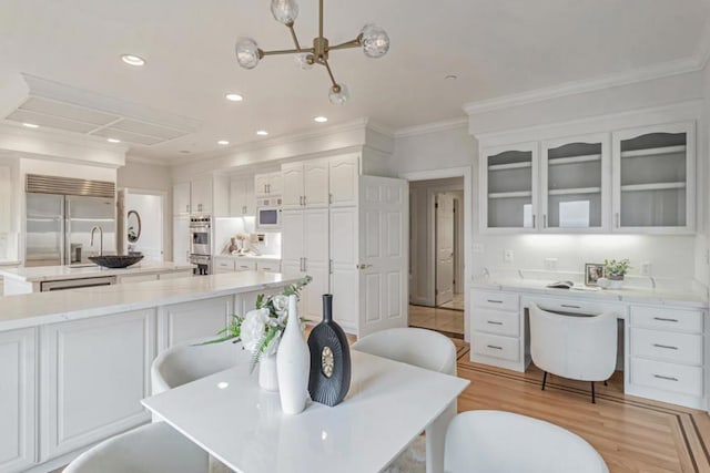 kitchen featuring white cabinets, stainless steel appliances, crown molding, light stone countertops, and a spacious island