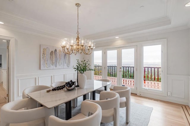 dining space featuring crown molding, light hardwood / wood-style flooring, a raised ceiling, and a healthy amount of sunlight