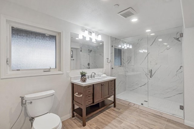 bathroom featuring wood-type flooring, vanity, an enclosed shower, and toilet