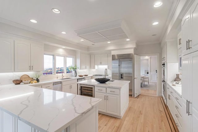 kitchen featuring light stone counters, sink, a kitchen island, and white cabinets