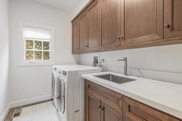 laundry area featuring sink, light tile patterned floors, washer and clothes dryer, and cabinets