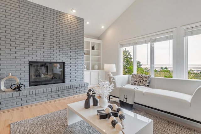 living room featuring wood-type flooring, high vaulted ceiling, and a fireplace