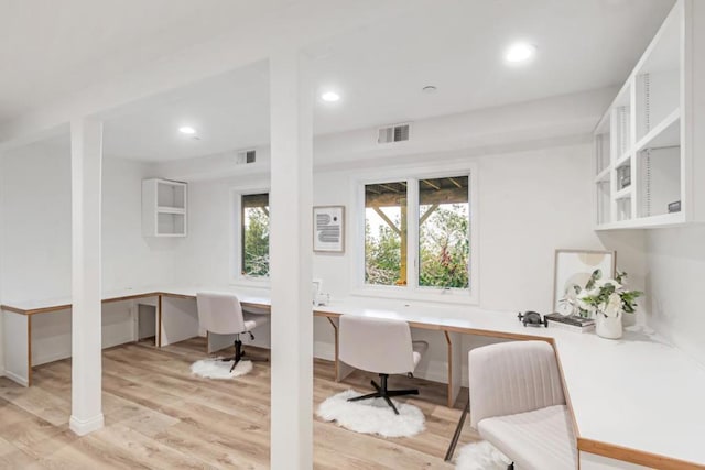 office with built in desk, light hardwood / wood-style flooring, and a wealth of natural light