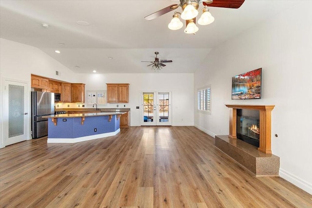 kitchen with a kitchen island, stainless steel refrigerator, lofted ceiling, sink, and a high end fireplace