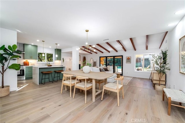 dining room with a chandelier, beam ceiling, and light hardwood / wood-style floors