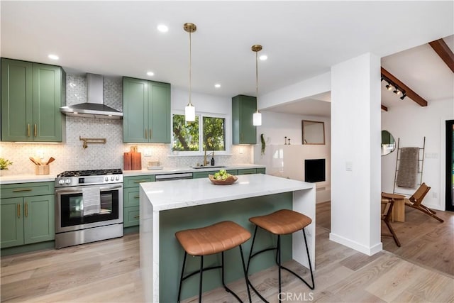 kitchen with sink, gas range, green cabinetry, and wall chimney exhaust hood