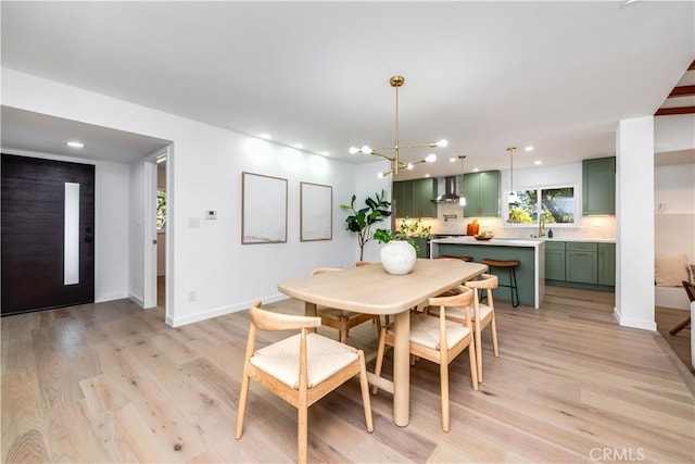 dining area with sink, a chandelier, and light wood-type flooring