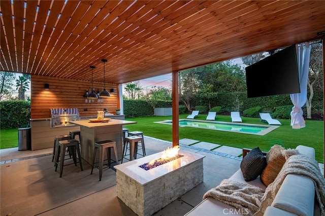 view of patio featuring a bar, grilling area, and an outdoor living space with a fire pit