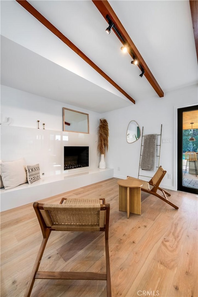 living room with beamed ceiling, hardwood / wood-style flooring, and track lighting