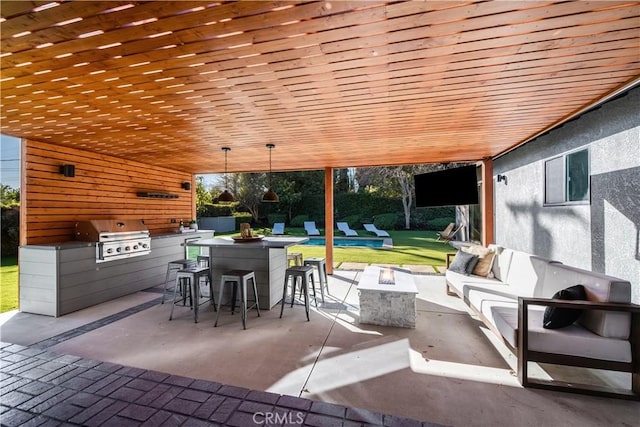 view of patio / terrace with exterior kitchen, exterior bar, area for grilling, and an outdoor living space with a fire pit