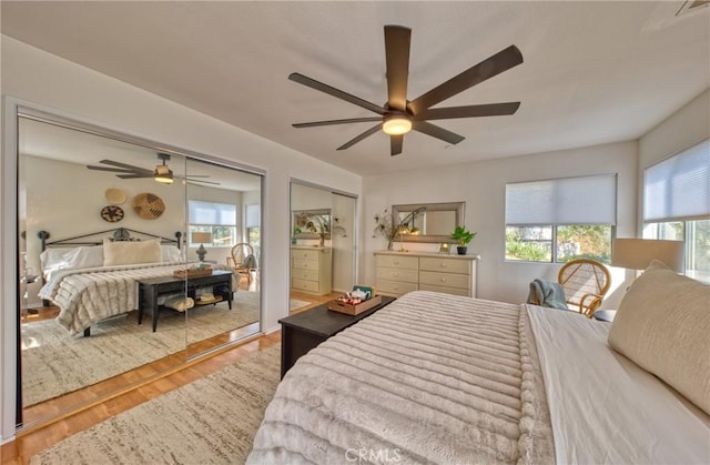 bedroom with hardwood / wood-style flooring, two closets, and ceiling fan