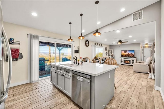 kitchen with sink, gray cabinetry, hanging light fixtures, a kitchen island with sink, and stainless steel appliances