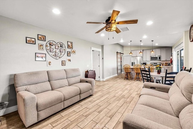 living room featuring light hardwood / wood-style floors, a barn door, and ceiling fan