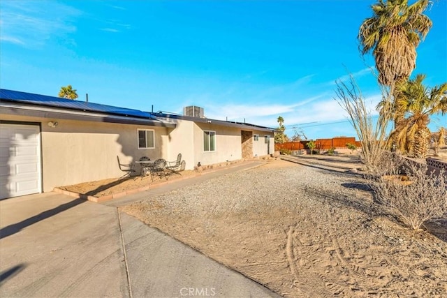 back of property featuring a garage, central air condition unit, and solar panels