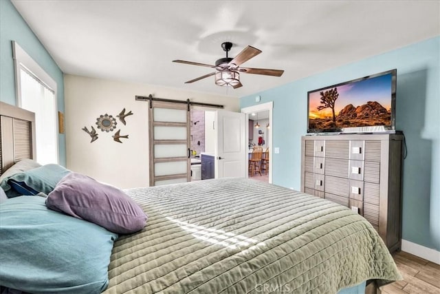 bedroom featuring ceiling fan and a barn door