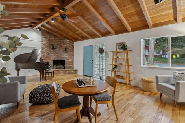 living room with wood ceiling, a brick fireplace, light hardwood / wood-style flooring, and vaulted ceiling with beams