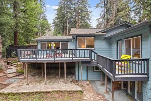 rear view of property featuring a wooden deck and a patio area