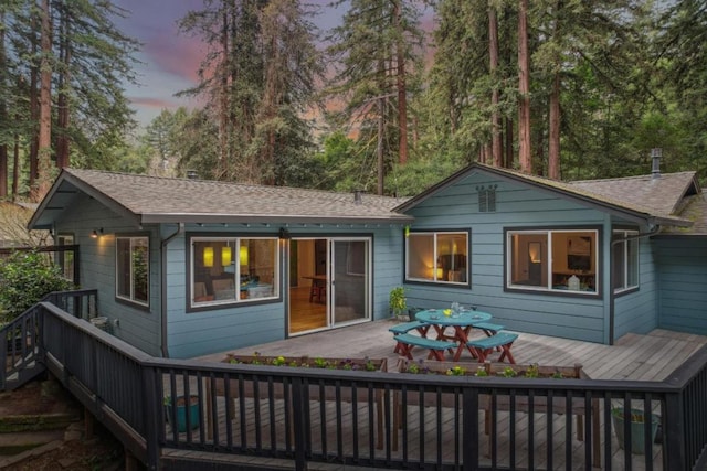 back house at dusk featuring a deck