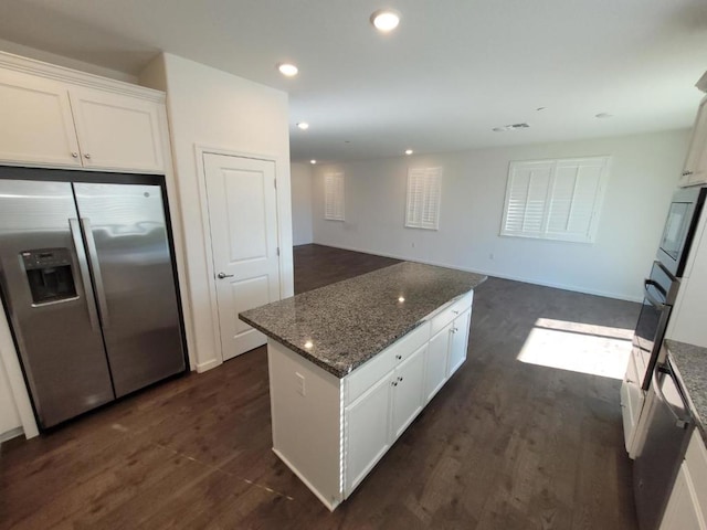 kitchen with white cabinetry, dark hardwood / wood-style floors, stainless steel refrigerator with ice dispenser, a kitchen island, and dark stone counters