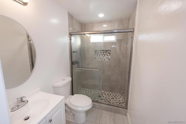 bathroom featuring toilet, vanity, and a shower with shower door