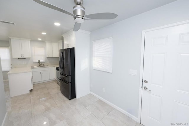 kitchen featuring black refrigerator, white cabinetry, sink, ceiling fan, and gas range