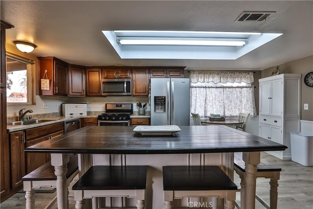 kitchen with butcher block countertops, visible vents, stainless steel appliances, and a wealth of natural light