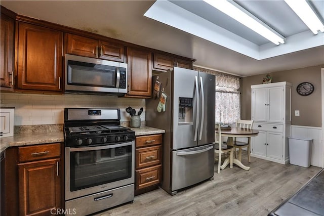 kitchen with light countertops, appliances with stainless steel finishes, backsplash, and light wood-style flooring