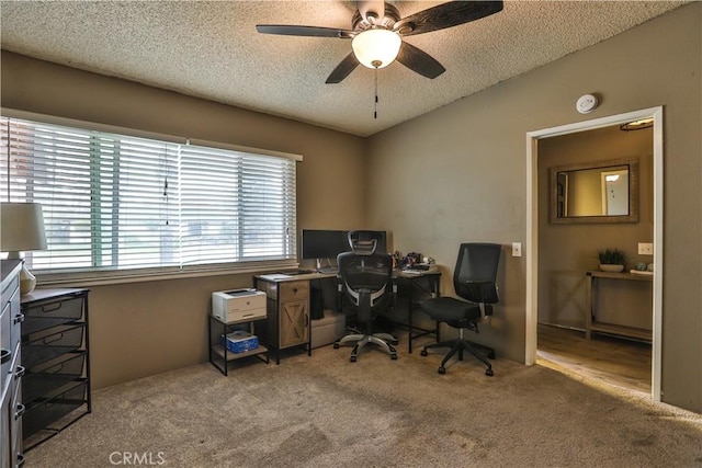 carpeted office space featuring lofted ceiling, ceiling fan, and a textured ceiling