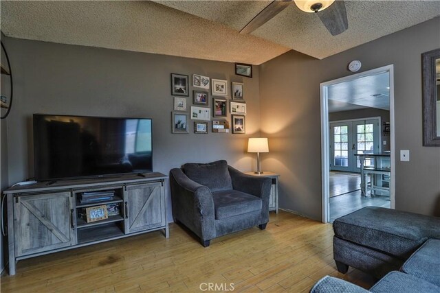 living room featuring hardwood / wood-style flooring, ceiling fan, a textured ceiling, and french doors