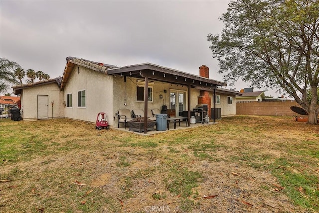 back of house with a chimney, fence, a yard, a patio area, and stucco siding