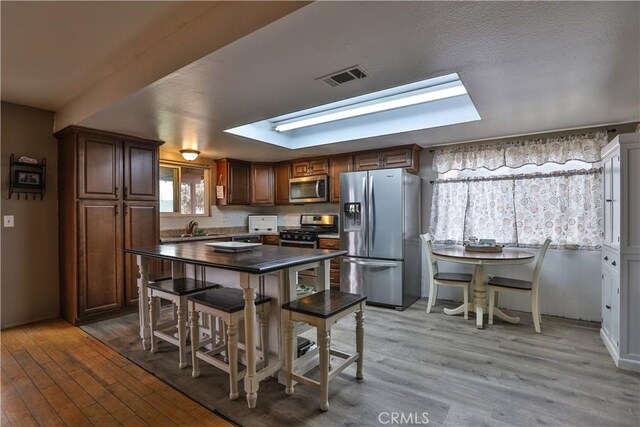 kitchen featuring appliances with stainless steel finishes, sink, and light hardwood / wood-style flooring