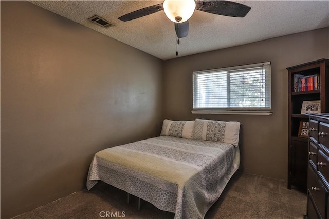 bedroom with visible vents, dark carpet, a textured ceiling, and ceiling fan