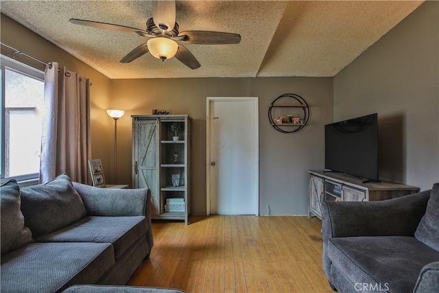 living area featuring ceiling fan, a textured ceiling, and light wood-style flooring